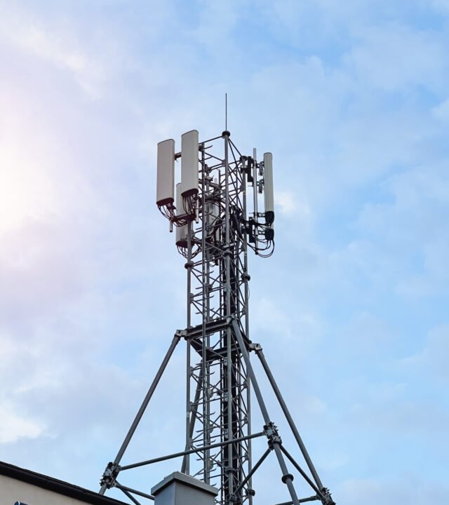 Macro Base Station. 5G radio network telecommunication equipment with radio modules and smart antennas mounted on a metal against cloulds sky background. Telecommunication tower of 4G and 5G cellular.