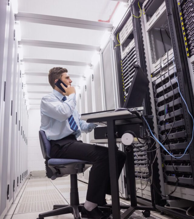 Technician talking on phone while looking servers in large data center